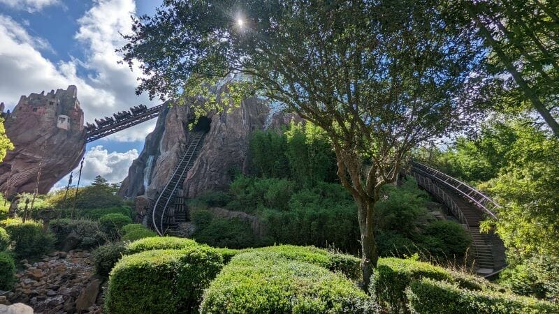 An Expedition Everest ride car summiting the mountain while the sun beams down through tree branches
