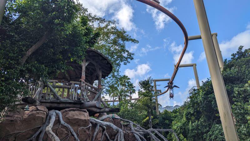 Riders starting their descent down the elevated track of Pteranadon Flyers over the Jurassic Park section of Islands Of Adventure