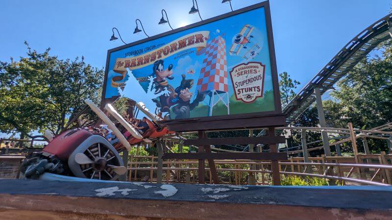 The Barnstormer train hurtles through a posterboard featuring Goofy