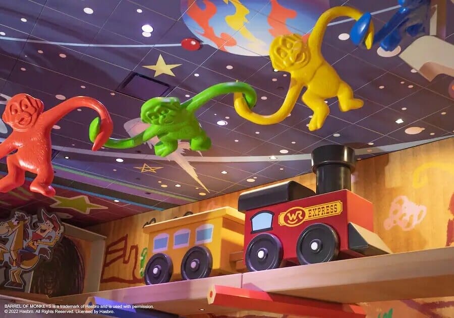 Looking at the ceiling in Roundup Rodeo BBQ with an oversized toy train and plastic monkeys from a Hasbro Game