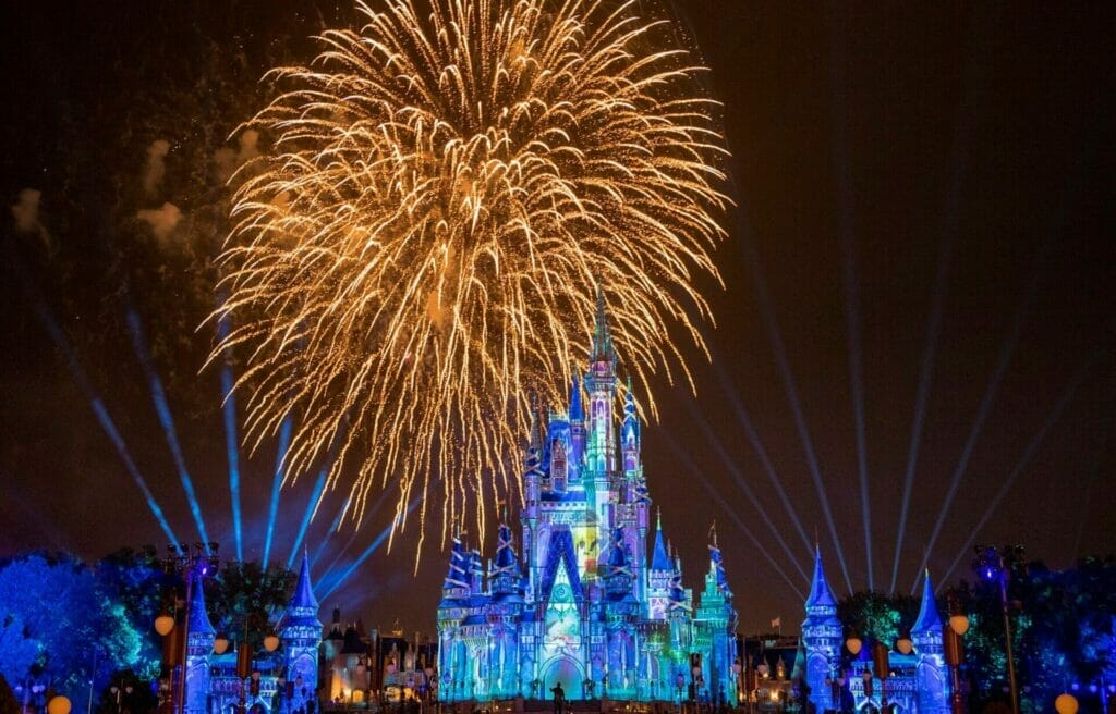 Giant fireworks explode over Cinderella Castle while lasters project fan like into the night sky.