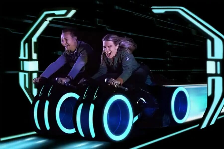 Riders holding on and smiling as their Tron Light Cycles launch
