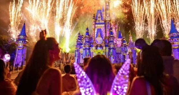 Family enjoying the fireworks exploding obove a lit up Cinderella Castle in Magic Kingdom.