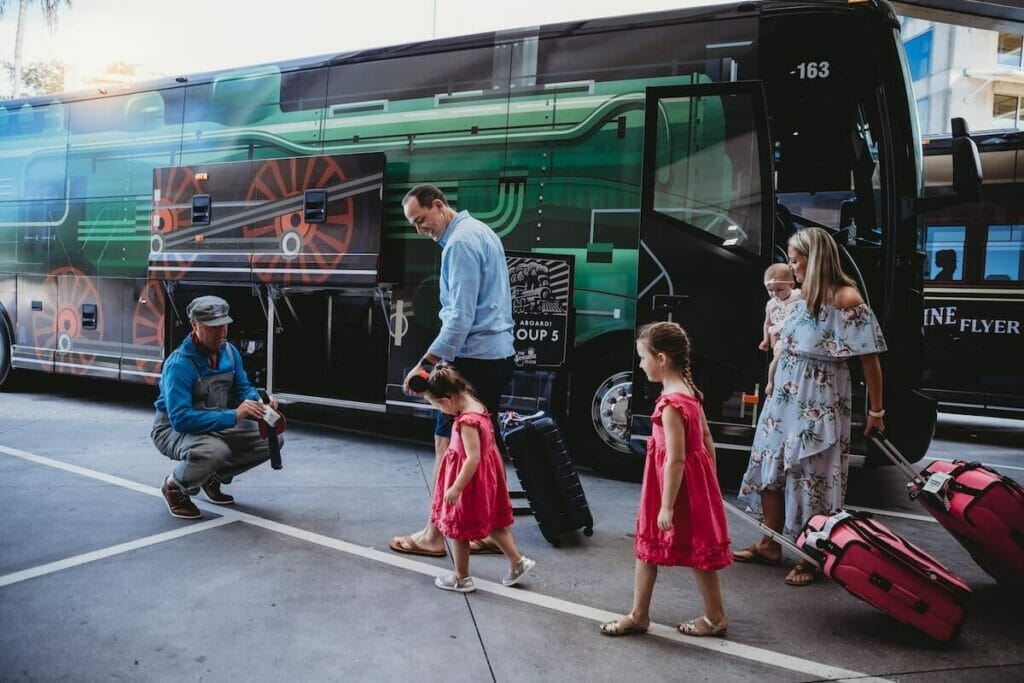 A young family excitedly on their way to Disney being met by one of the Sunshine flyer staff in front of a bus