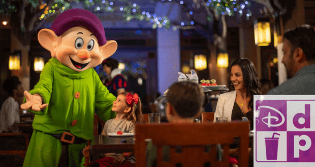 Dopey standing in front of guests eating at a table service restaurant along with the Disney Dining Plan logo