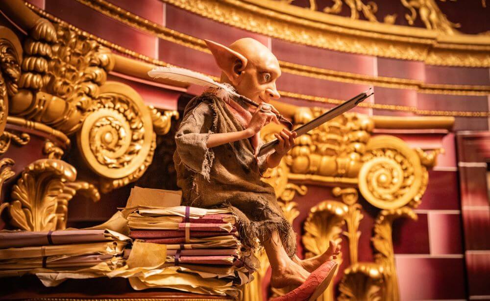 An animatronic of her former house elf, Higgeldy sitting on a pile of books.