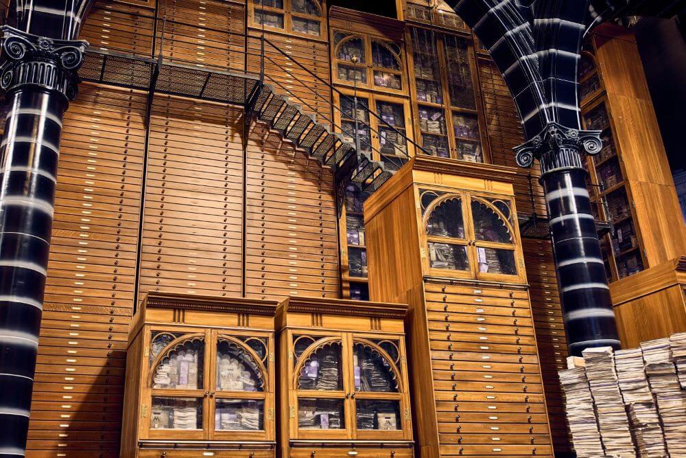Lots of wooden cabinets, drawers and stairs in the Magical Archives.