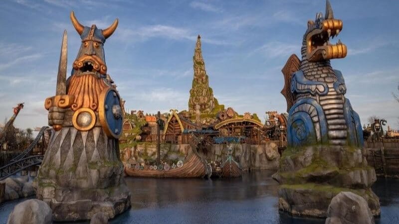 Official Isle Of Berk Photo looking across to Mead Hall from the entrance over the lake with 2 imposing statues in the foreground.